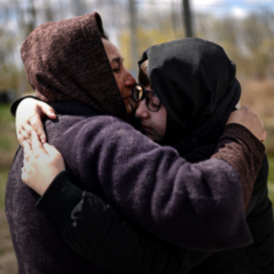 Cover of "Mapping of good practices in family reunification for unaccompanied and separated children and adolescents" report featuring two people embrace after reuniting on their way back home at a border crossing